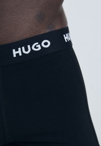 Boxers noirs avec une taille élastique douce ornée du logo "HUGO" en blanc. Fabriqués en tissu lisse et extensible pour un confort optimal.