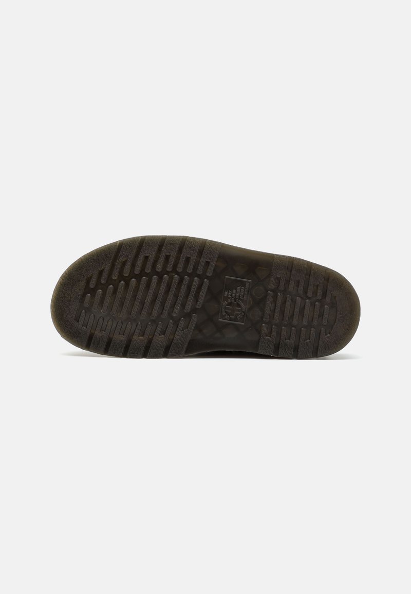 Suela de zapato de goma negra con un patrón de agarre texturizado que presenta surcos y crestas, garantizando tracción en diversas superficies.
