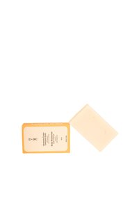 Burro per il corpo a forma rettangolare, di colore beige chiaro, con una superficie leggermente testurizzata. Accompagnato da una scatola gialla con etichette.