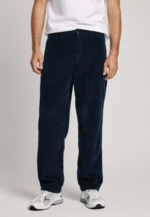 Pantalones de pana de color navy con corte recto, que presentan surcos texturizados, un cierre frontal de botón y dos bolsillos laterales, combinados con zapatillas blancas.