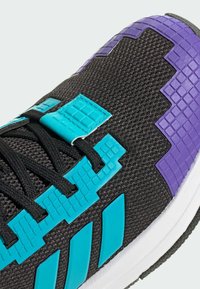 Čierna atletická obuv s textúrovaným sieťovým zvrškom, tyrkysovými a fialovými pixelovanými akcentmi a výrazným dizajnom troch pruhov po strane.