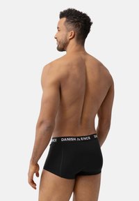 Černé boxerky vyrobené z měkkého materiálu, s širokým elastickým pasem, na kterém je v bílé barvě vytištěno jméno značky "DANISH".