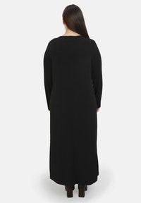 Langes schwarzes Kleid mit langen Ärmeln und geradem Schnitt. Glatte Textur, minimales Design ohne sichtbare Muster oder Verzierungen.