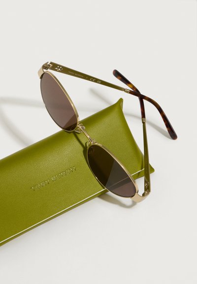Sunčane naočale s zlatnim okvirom i smešnim staklima, ovalnog oblika. U kompletu s teksturiranom zelenom kožnom futrolom u kojoj je utisnuto "TORY BURCH."