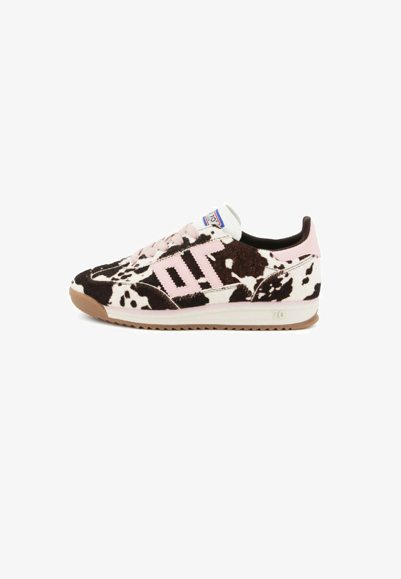 Sneaker a taglio basso con stampa maculata bianca e nera, dettagli rosa, suola marrone chiaro e lacci rosa, mostrato di lato su uno sfondo bianco.