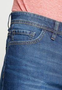 Denim jeans with a dark blue wash, featuring a classic five-pocket design, contrast stitching, and a straight leg silhouette.
