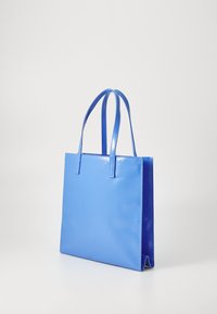 Modrá taška s lesklým povrchom, obdĺžnikového tvaru, s dvoma dlhými rúčkami. Navrhnutá s plochým dnom pre stabilitu.
