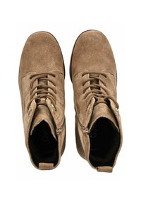 Bottines en suède marron, à bout rond, avec un devant lacé, des fermetures éclairs sur le côté et un intérieur court et rembourré. Semelles plates avec un motif de sculpture minimal.