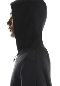 Musta hupullinen collegepaita, jossa on sileä pinta ja kiristysnyöri. Siinä on minimalistinen muotoilu ja rintakehässä logo, esitetty sivuprofiilista.