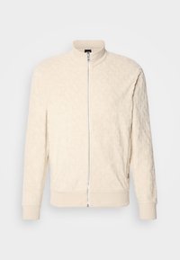 Krämfärgad plyschjacka med dragkedja, ribbade ärmar och krage, med en subtil texturerad mönstring och framdragkedjestängning.