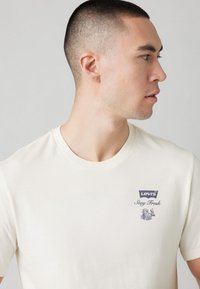 Cream-colored T-shirt made of cotton, featuring a Levi's logo and "Stay Fresh" print in navy. Classic fit with a crew neckline.
