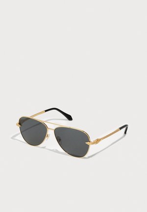 Lunettes de soleil aviateur en métal doré avec des verres gris foncé. Caractéristiques : branches fines, accents texturés et embouts noirs sur les branches.