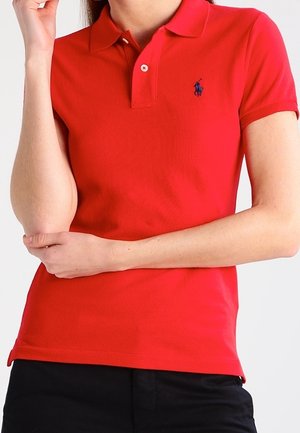Rød polo skjorte lavet af bomuld med krave, korte ærmer og et lille blåt broderet logo på venstre bryst.