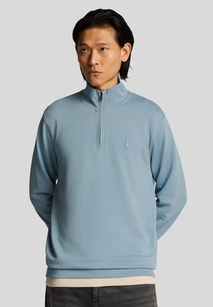 Lichtblauwe pullover sweatshirt met een ritssluiting bij de kraag en geborduurd logo. Gemaakt van zacht materiaal, met lange mouwen en een relaxte pasvorm.