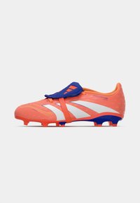 Botín de fútbol naranja con una correa y detalles azules, que presenta una parte superior texturizada y un diseño blanco. Suela con tacos para mayor tracción.