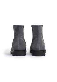 Bottines en daim gris foncé avec une texture lisse, bout rond et semelle en caoutchouc noir. Équipées d'une fermeture éclair sur le côté pour un enfilage facile.