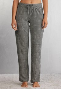 Zwart-witte geblokte broek met een ontspannen pasvorm, voorzien van een verstelbare trekkoordtaille en zachte stof. Soepele textuur en rechte benen.