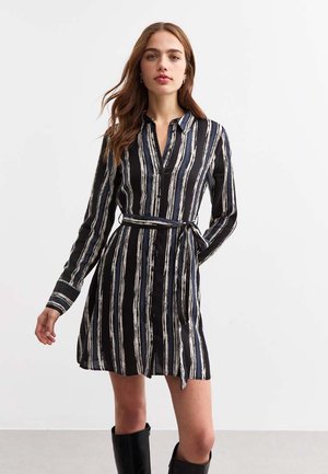 Black button-up dress with vertical white stripes, long sleeves, belted waist, and a relaxed fit. Smooth fabric with a polished sheen.