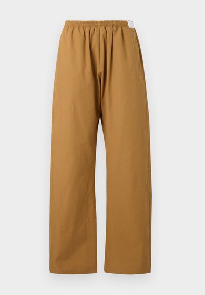 Calças largas numa tonalidade castanha quente. Feitas de algodão, com um cós elástico para conforto. Textura suave, sem padrões ou adornos visíveis.