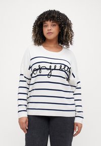 Pulover alb cu dungi orizontale bleumarin, având un mesaj brodat în negru "joyfully" pe față și un croi relaxat cu mâneci ampla.