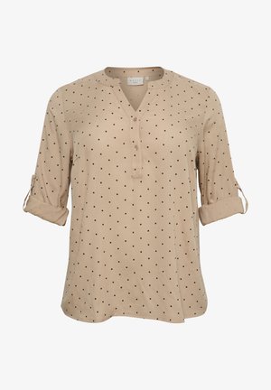 Beige shirt with black polka dots, V-neckline, and roll-up sleeves. Soft fabric with a relaxed fit and subtle texture. Two buttons at the neck.