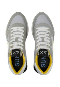 Zapatillas deportivas grises con materiales de malla y ante, cordones blancos, acentos amarillos y plantillas negras con "SUN" en azul.