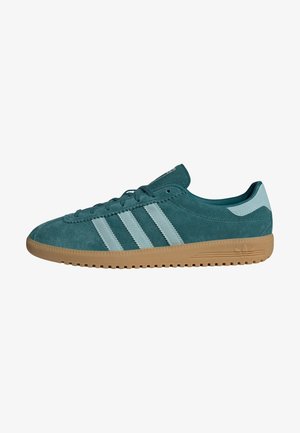 Niskie sneakersy z miękkiego zamszu w kolorze zielonkawoniebieskim z jasnoniebieskimi paskami i pętelką na pięcie, beżową gumową podeszwą i sznurowanym zapięciem.