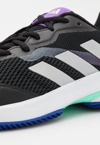 Černé sportovní boty s prodyšným materiálem, stříbrnými pruhy, fialovými akcenty a texturovanou podrážkou v modré a zelené barvě.