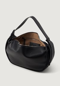 Sac à épaule noir en cuir avec une surface texturée, une forme arrondie et une sangle réglable. L'intérieur comprend une poche zippée et un revêtement beige.