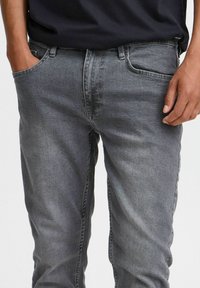 Grijze denim jeans met een aansluitend ontwerp, voorzien van vijf zakken, een subtiele vervaagde textuur en reguliere stiksels bij de naden en zakken.