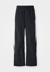 Pantalon de survêtement noir en nylon avec une taille élastique, dotés de panneaux latéraux blancs et d'un subtil détail de logo à l'avant.