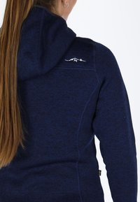 Felpa blu navy, tessuto a maglia, con un logo di montagna bianco sulla spalla. Cappuccio aderente, con dettagli nelle cuciture laterali e una vestibilità comoda.