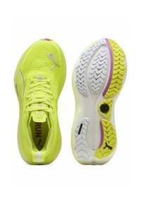 Baskets de course jaunes vives avec tige en mesh, arborant un logo argenté et une semelle en caoutchouc texturée avec un motif de profil distinct et des accents violets.