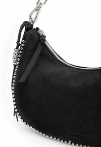 Sac à bandoulière en daim noir avec des accents en perles argentées le long du bord, fermeture éclair, et une bandoulière détachable. Texture lisse, silhouette incurvée.