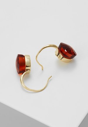 Paire de boucles d’oreilles à crochet en or avec de grandes pierres précieuses rouges profondes facettées, serties dans des chatons ronds sur une surface blanche.