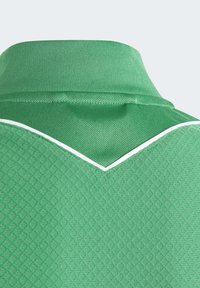 Polo verde con un motivo testurizzato. Presenta un colletto a coste e un accento bianco a contrasto lungo il collo a forma di V.
