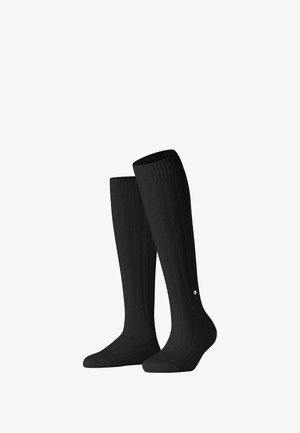 Chaussettes noires montantes avec texture côtelée, présentant un petit logo près de la cheville. Fabriquées en matériau flexible et durable.