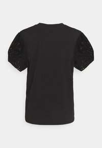 Camiseta negra con mangas cortas abullonadas de encaje texturizado, con cuello redondo y corte holgado. Vista posterior mostrada.