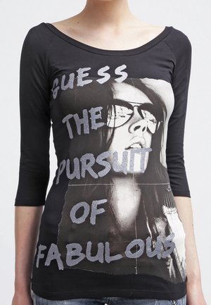 Czarna koszulka z długim rękawem z nadrukiem graficznym przedstawiającym kobietę w okularach przeciwsłonecznych oraz błyszczącym napisem "GUESS THE PURSUIT OF FABULOUS."