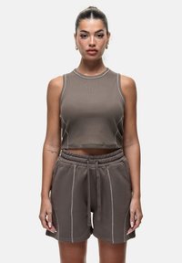 Bruin gecropte tanktop met een geribbelde textuur en ronde halslijn, gecombineerd met bijpassende hoge shorts met witte stiksels en een elastische tailleband.