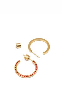 Boucles d'oreilles en métal doré avec des embellissements en forme de cœur rouge, présentant une texture métallique lisse et des composants détachables pour un design ajustable.