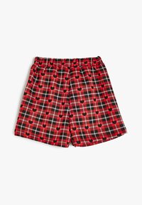 Pantalones cortos de cuadros rojos con un patrón de corazones, acentos en blanco y negro, cintura elástica y un corte relajado con bolsillos laterales.