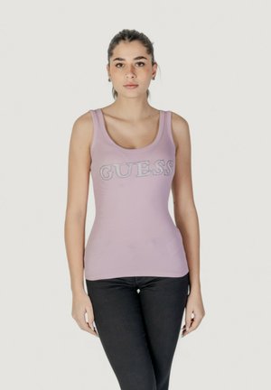 Canottiera senza maniche lilla con "GUESS" in glitter argento, vestibilità aderente, texture a coste, indossata con jeans neri.
