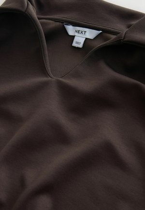 Brązowa koszulka z dekoltem w serek wykonana z miękkiego materiału, charakteryzująca się gładką fakturą i subtelnym połyskiem. Etykieta z napisem "NEXT" wskazuje na markę.