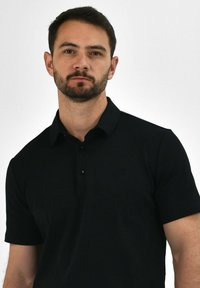 Black polo shirt with short sleeves, featuring a collared neck and three-button placket. Made from smooth, lightweight fabric.
