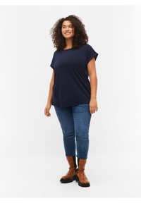Marinblåt kortärmad topp med en lös passform, kombinerad med medeltvättade jeans och bruna ankelskor med tjock sula.