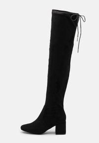 Botas negras por encima de la rodilla hechas de suave ante, con un tacón cuadrado y un detalle de lazo en la parte superior para su ajuste.