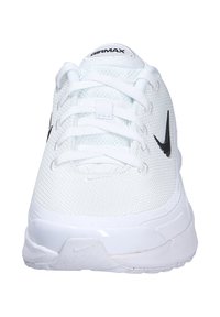 Zapatillas deportivas blancas con parte superior de malla, cierre de cordones, logo negro de Nike en el lateral y suela blanca acolchada.