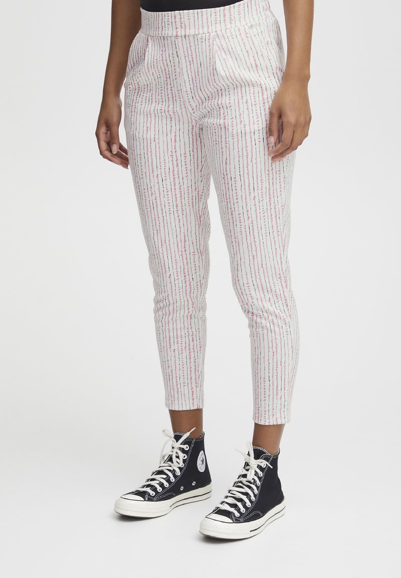 Witte broek met roze verticale strepen, met een aansluitend ontwerp en zakken. Combinatie met zwarte hoge sneakers.