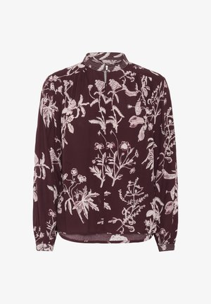 Dlhý rukáv marhuľový blúzku s prepracovanými kvetinovými vzormi vo svetloružovej farbe, s gombíkovým golierom a jemnými plisovanými detailmi.